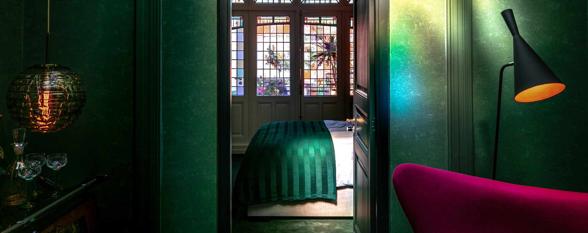 Sfeervolle kamer van B&B N10 in Roermond met groen interieur, glas-in-loodramen en warme verlichting, inspirerend beeld voor overnachten in Limburg.