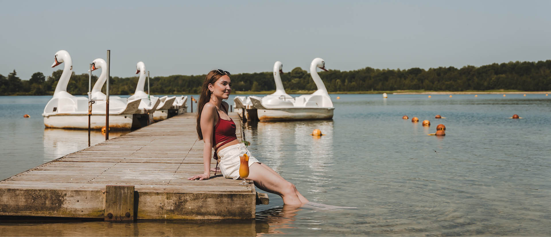 meisje met haar voeten in het water met een cocktail