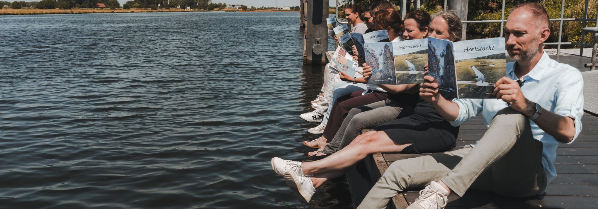Team van Hart van Limburg presenteert het Hart van Limburg Magazine Hartstocht aan het water.