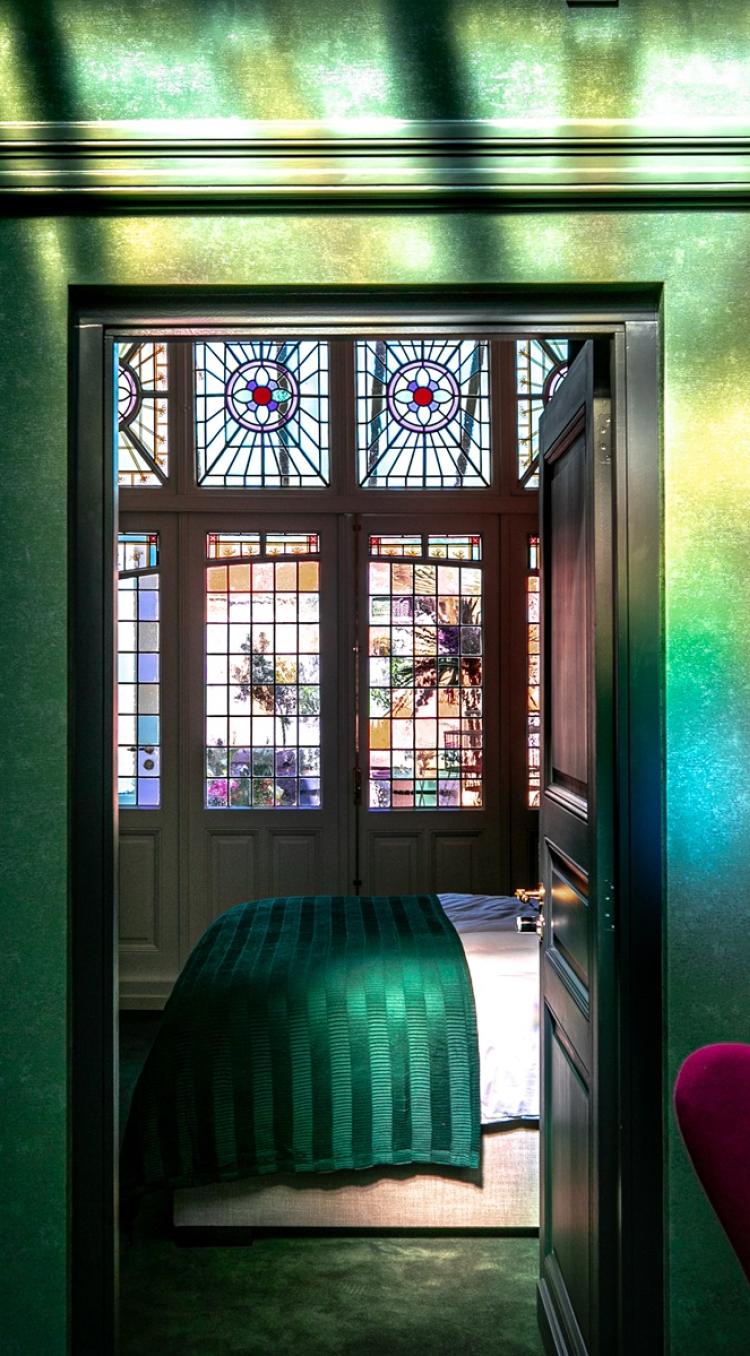 Sfeervolle kamer van B&B N10 in Roermond met groen interieur, glas-in-loodramen en warme verlichting, inspirerend beeld voor overnachten in Limburg.