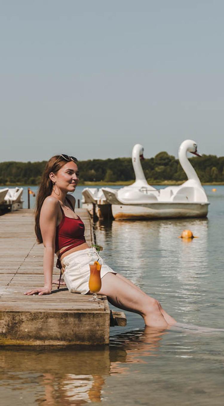 meisje met haar voeten in het water met een cocktail