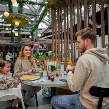 Gezin aan het eten bij restaurant Via Verde bij de Leistert, in een groene en sfeervolle setting.