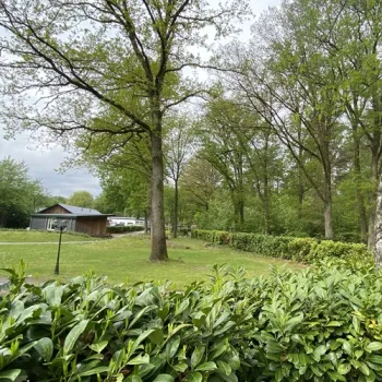 Groepsaccommodatie op Landgoed Leudal, omringd door grasveld, bomen en bosrand.