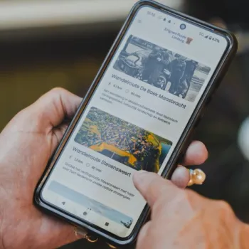 Een persoon houdt een smartphone vast met daarop geopend de Erfgoed Route App
