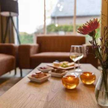 Sfeervolle woonkamer van vakantiehuis Eindeloos Asselt, met hapjes op tafel, kaarslicht en uitzicht op de tuin.