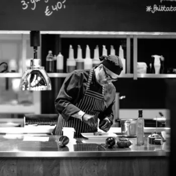 Zwart wit foto van de chefkok van Porto Maurizio die bezig is met een gerecht in de keuken