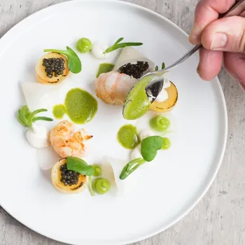 Verfijnd gerecht van Restaurant Marrees met zeevruchten, groene saus en delicate opmaak op een wit bord.