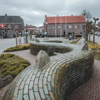 Drakenstaart in Beesel, een gebogen stenen kunstwerk op een plein dat verwijst naar de legende van Sint Joris en de draak.