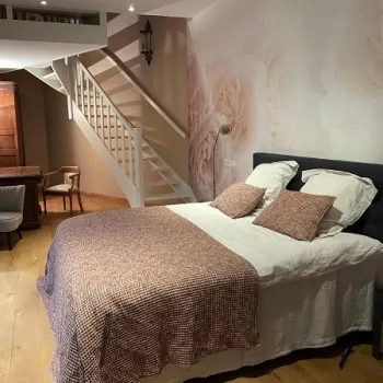 Slaapkamer van B&B Het Doctershoes met tweepersoonsbed, zachte tinten en trap naar een hoger gelegen deel van de kamer.
