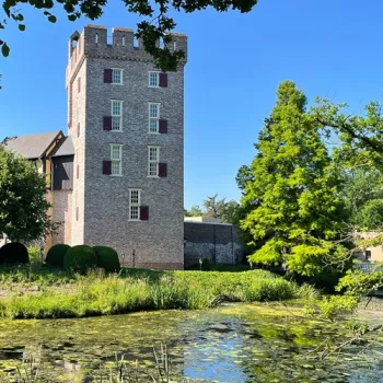 Kasteel Daelenbroeck met toren, omringd door groen en een gracht in het landschap van het Roerdal.
