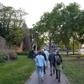 Groep mensen tijdens de Heksenwandeling in Roermond, wandelend langs groen en historische muren richting de Rattentoren in Roermond
